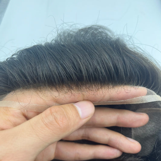 French lace front between fingers showing transparent mesh and hand-tied dark baby hairs