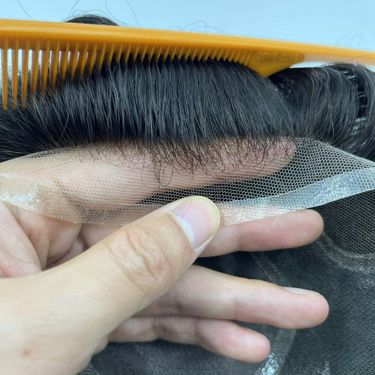 French lace front edge with orange comb showing fine mesh and hand-tied black baby hairs