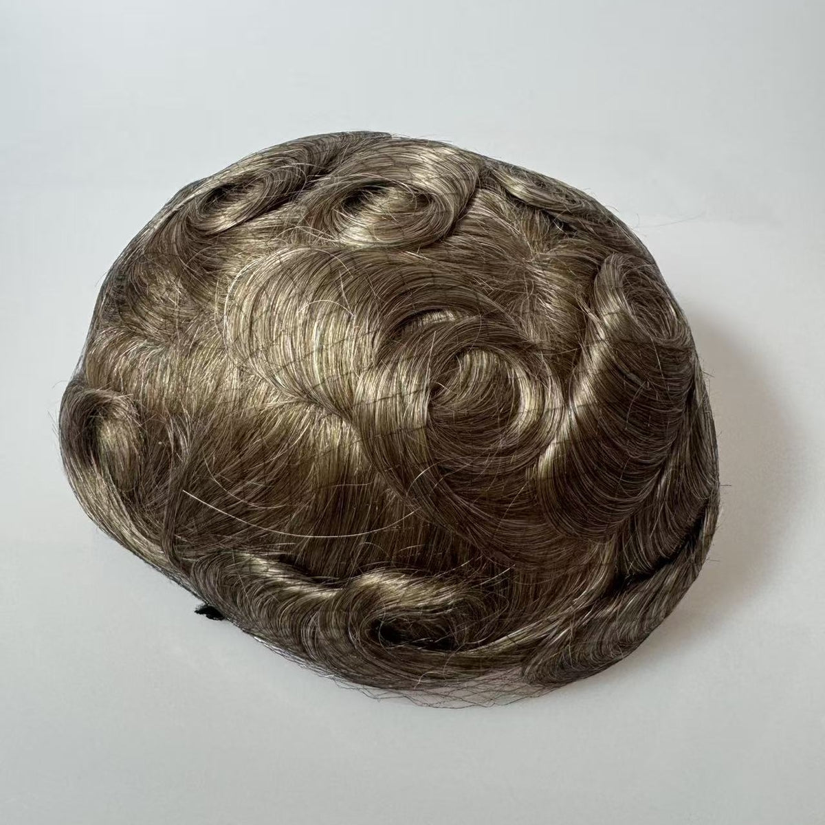 Top-down view of wavy brown hair system with grey blend showing natural parting pattern