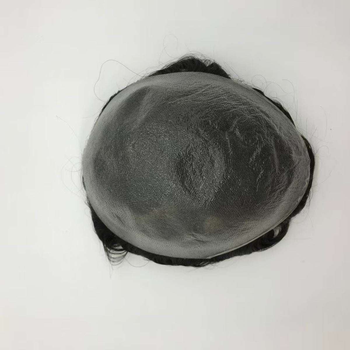 Top-back view of Ultra Thin poly skin base showing flat gray surface with curly hair