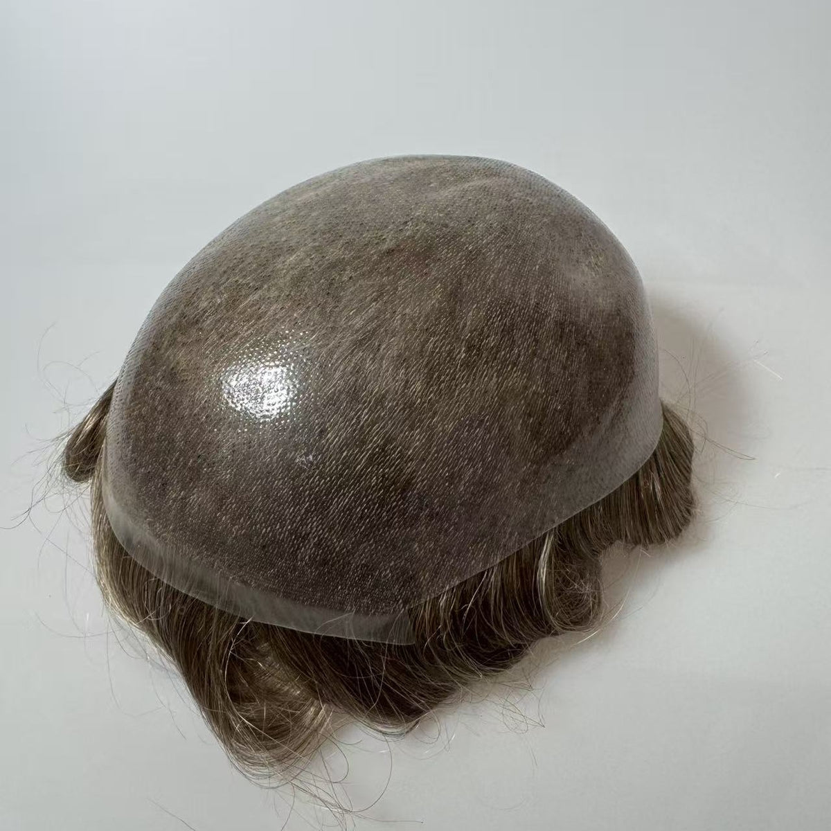Top view of thin poly knotted skin hair system base showing transparent knotted crown and wavy hair, 8x10 size